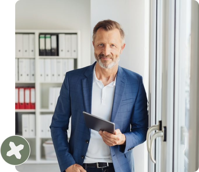 Businessman smiling with arms crossed in modern office.