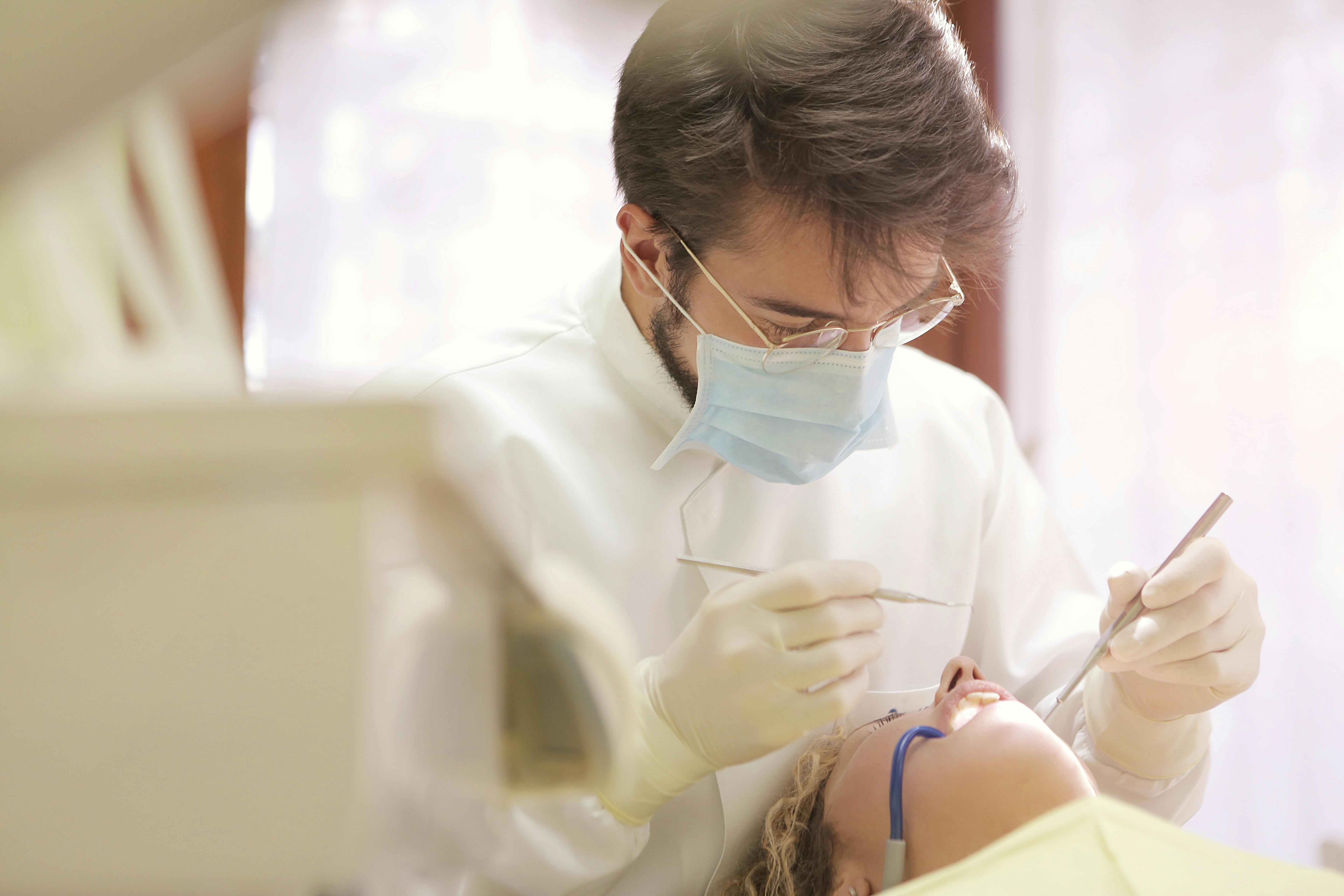 dentist reviewing a patients mouth with dental equipment