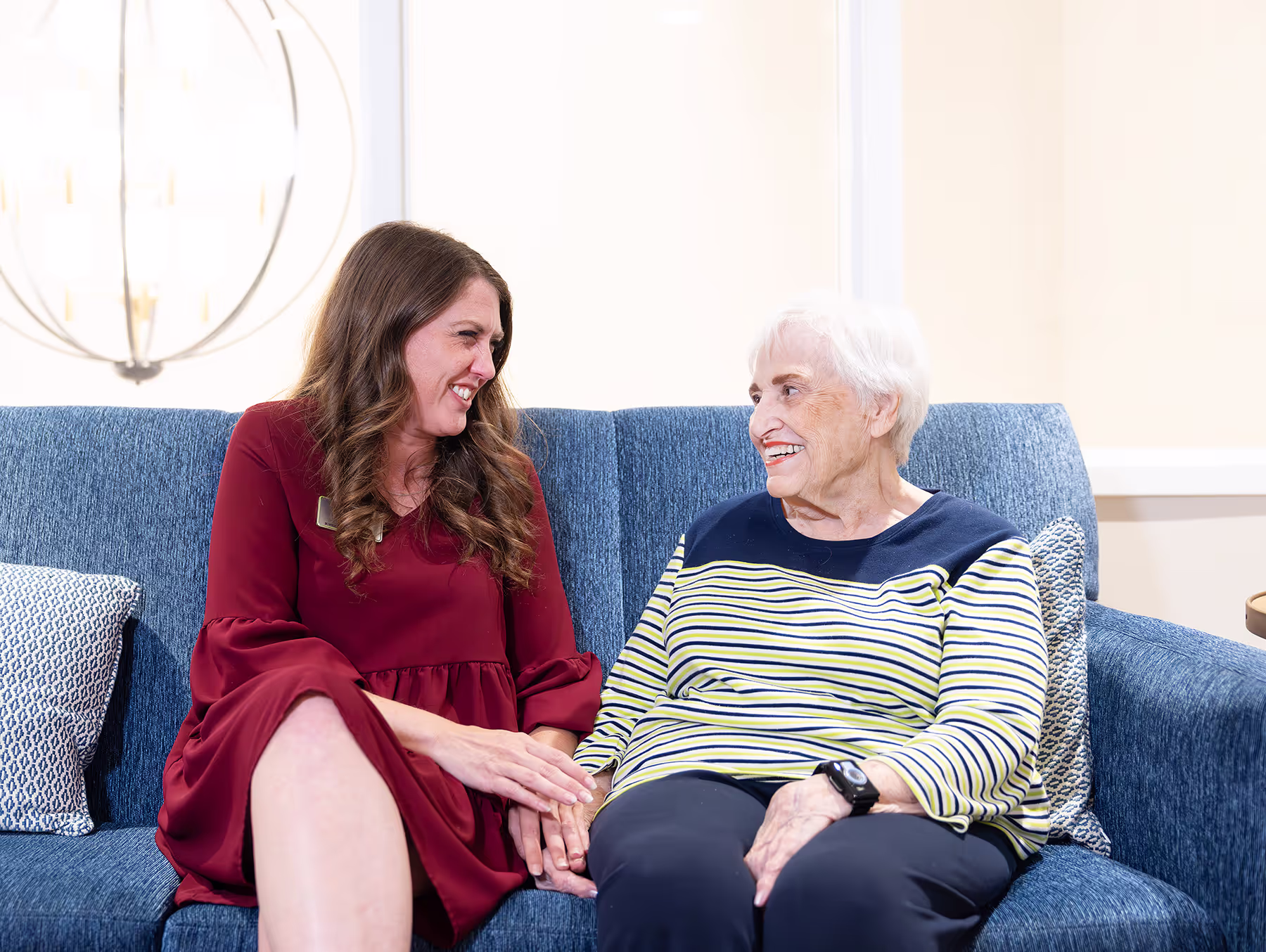 Two people sitting on a couch, smiling and holding hands.