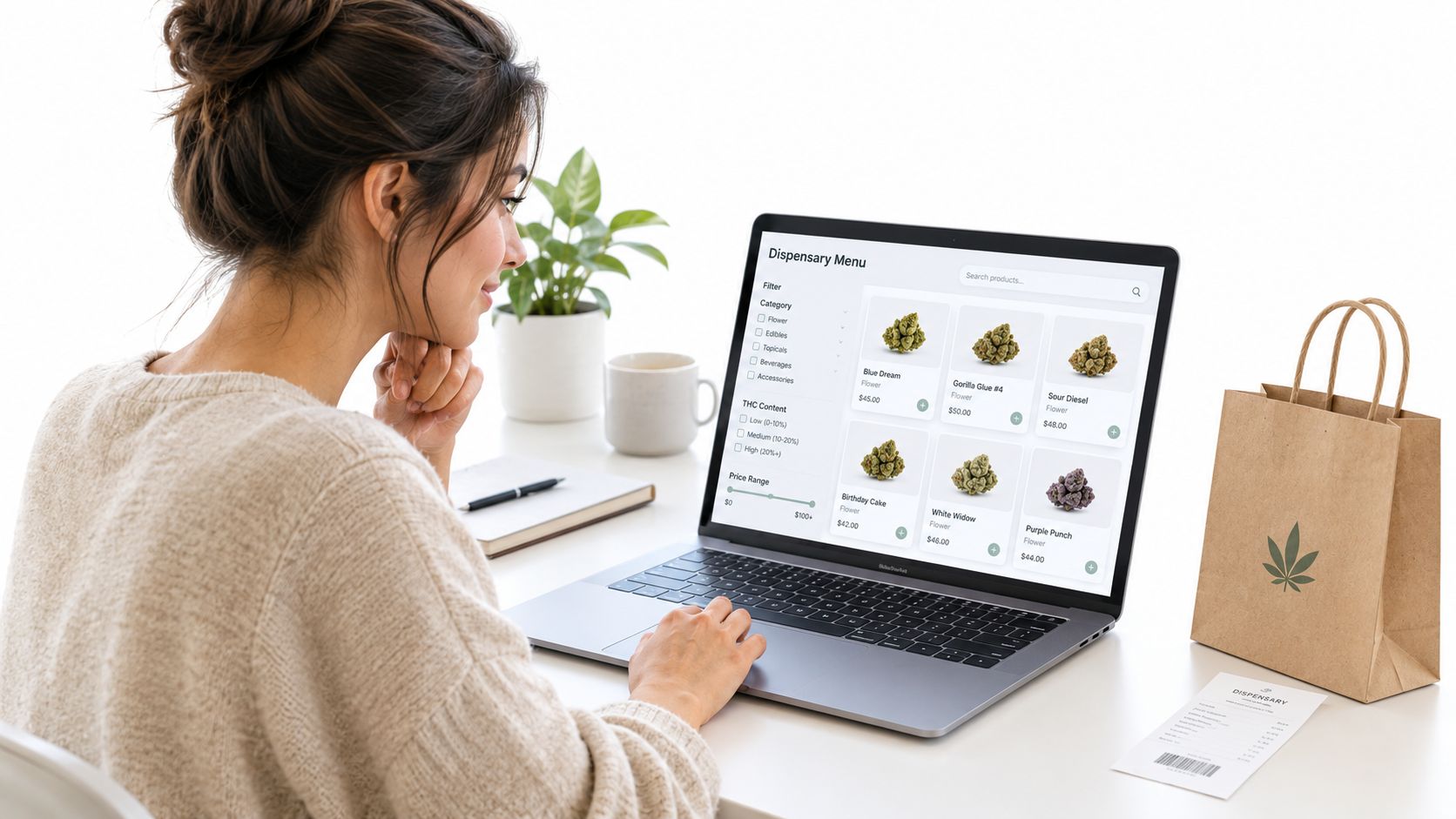A woman browsing an online cannabis dispensary menu on her laptop with a shopping bag nearby.