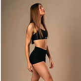 A woman in a black bikini top and shorts.