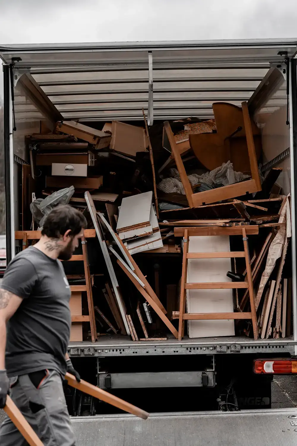 EntrümpelungRLP MItarbeiter trägt Holzteile in den LKW