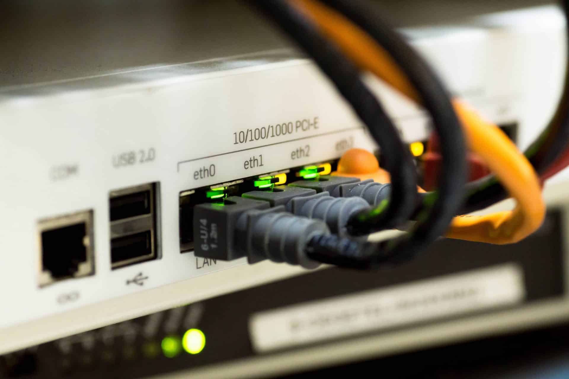 Several network cables plugged into a router with illuminated indicator lights.