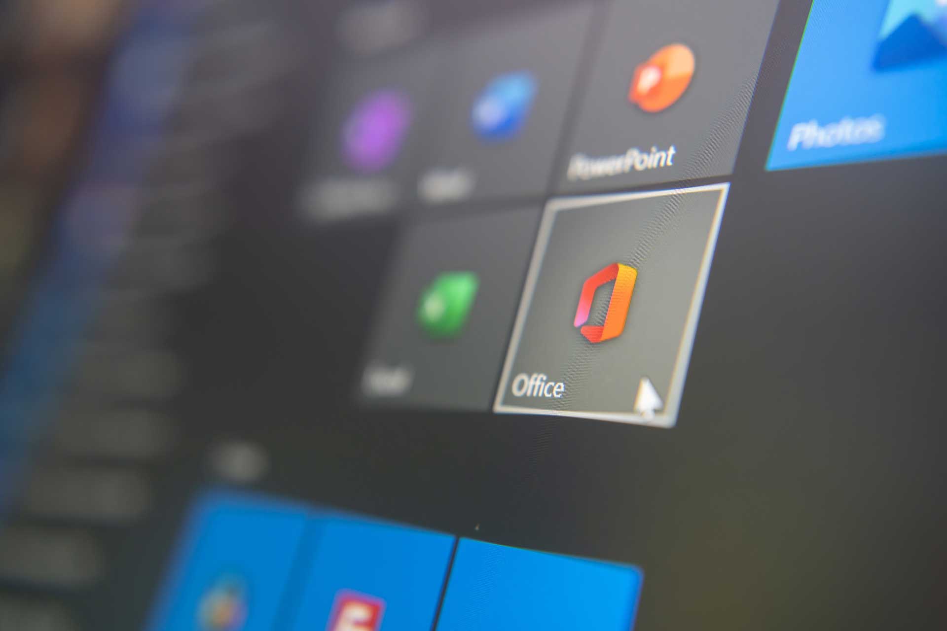 A computer screen displays the Microsoft Office application icon prominently among other software icons.