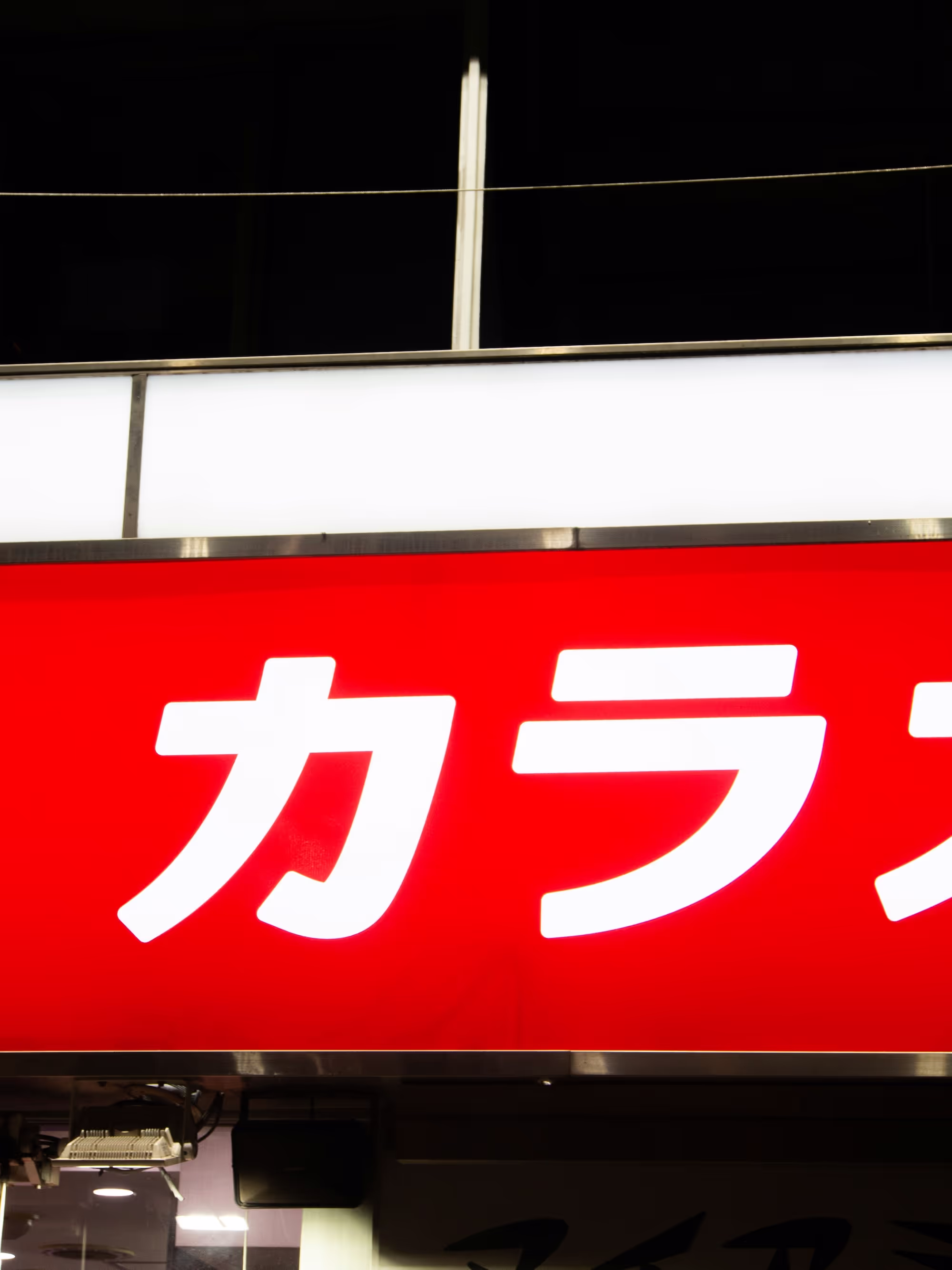 Illuminated red sign with white Japanese katakana characters.