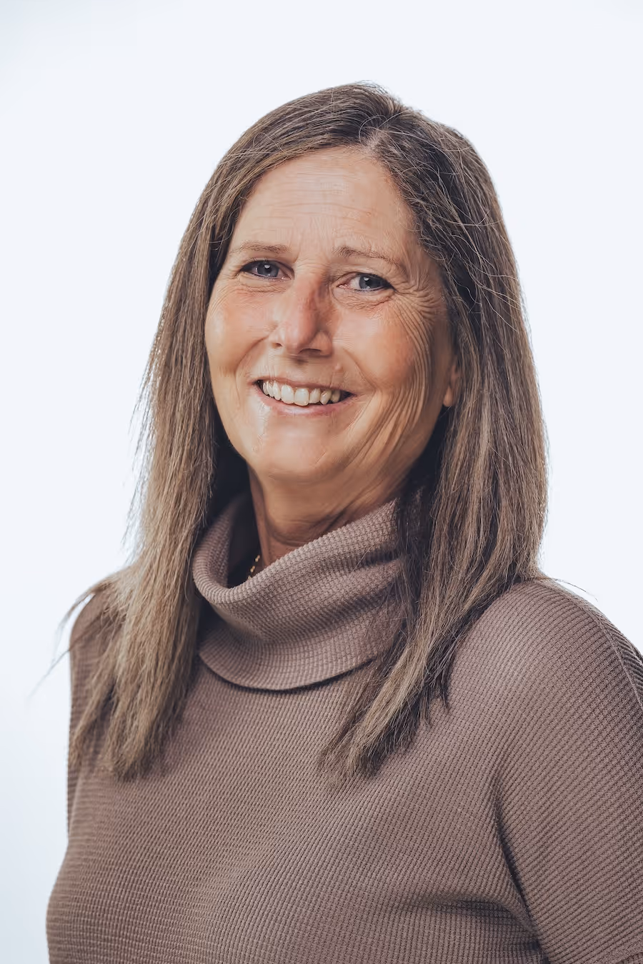 Smiling middle-aged woman with straight brown hair wearing a brown turtleneck sweater.