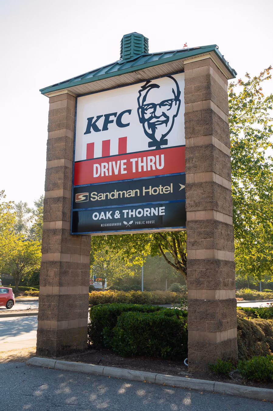 Outdoor sign with KFC Drive Thru, Sandman Hotel, and Oak & Thorne Neighborhood Public House.