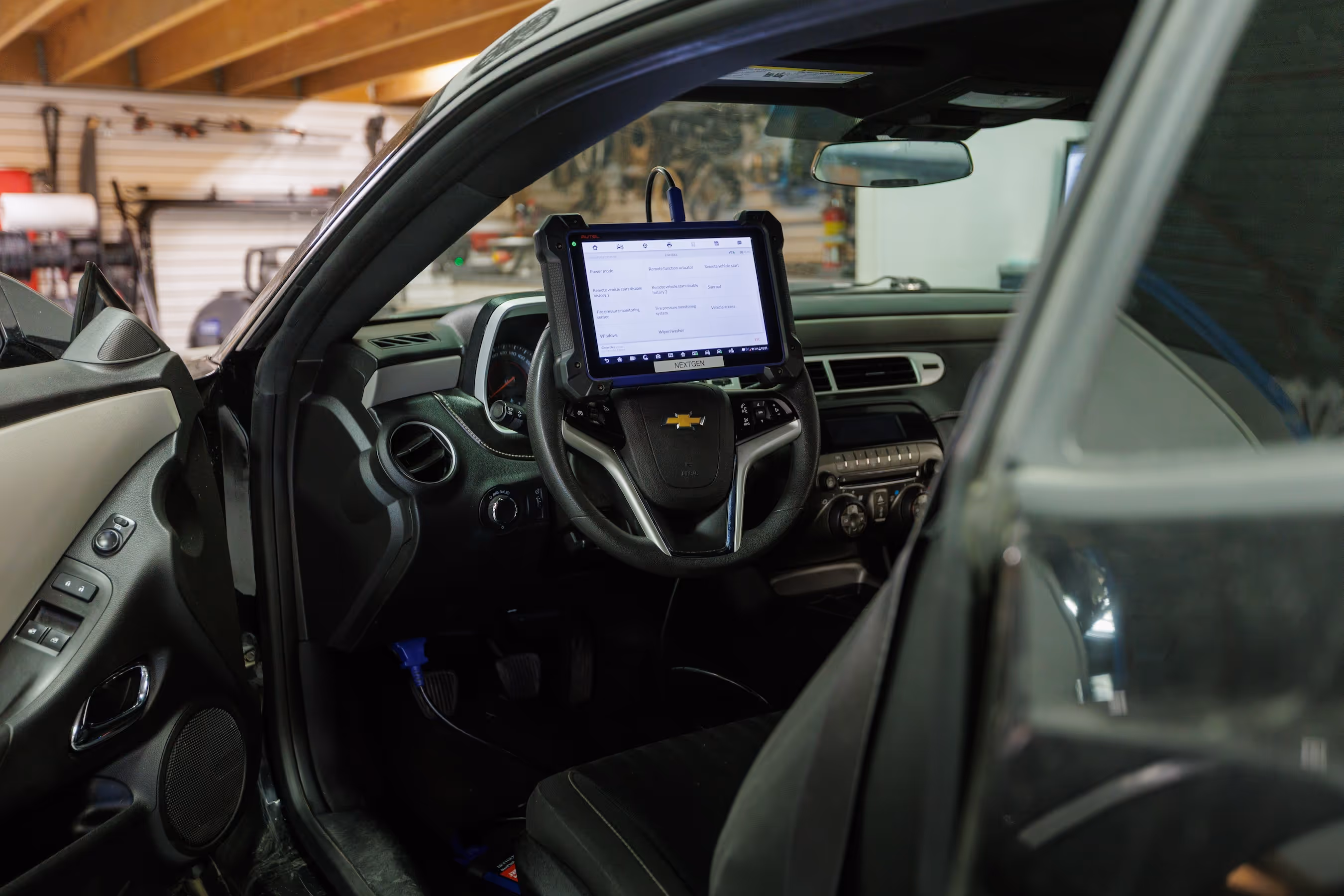 Interior of a Chevrolet car with a diagnostic tablet mounted on the steering wheel displaying vehicle data.