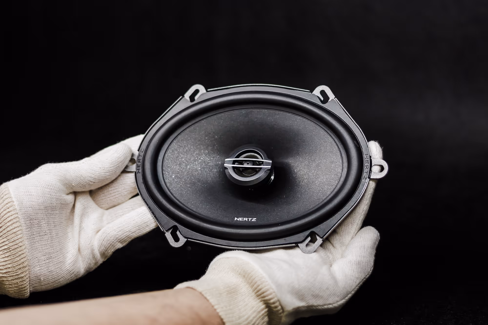 Close-up of two black loudspeakers facing each other on a purple background.