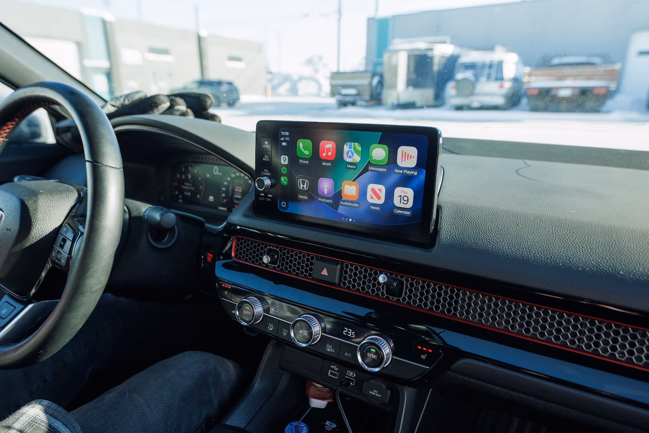 Car dashboard showing steering wheel, digital instrument panel, and touchscreen infotainment system with apps interface.