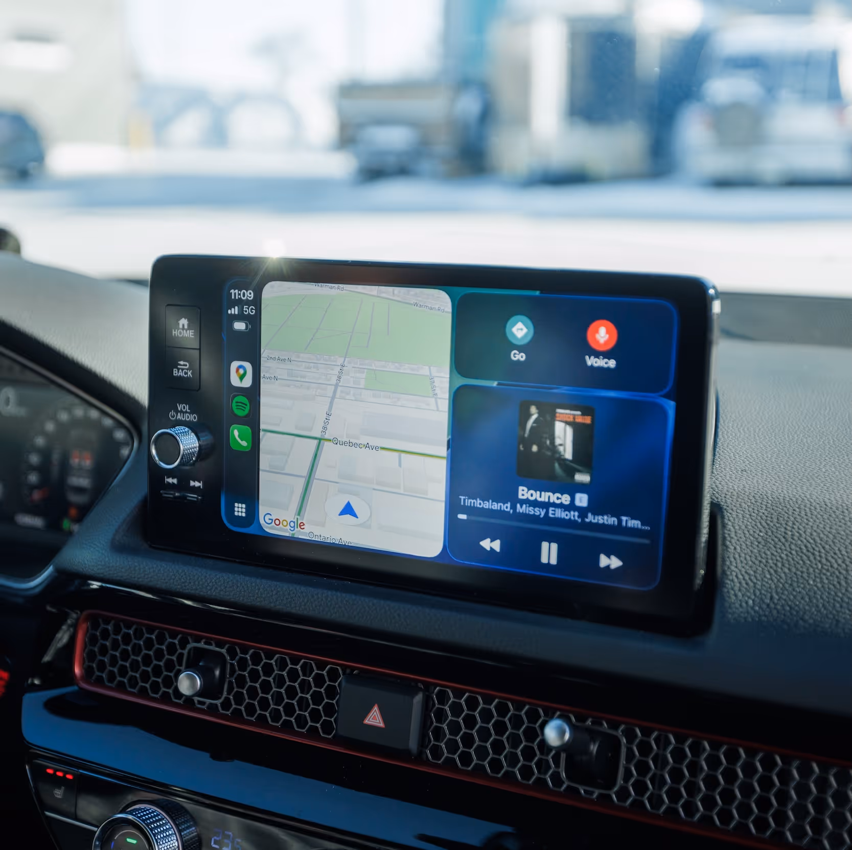 Car dashboard touchscreen displaying navigation map and music player with song 'Bounce' by Timbaland, Missy Elliott, and Justin Timberlake.