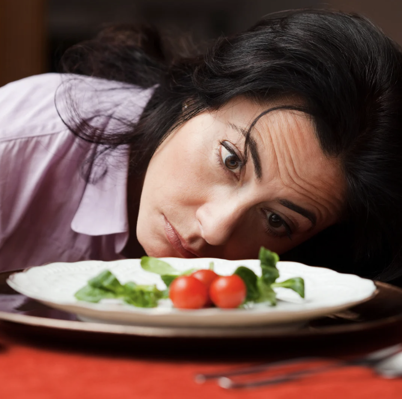 a white woman with brown hair  dreads eating a tiny salad