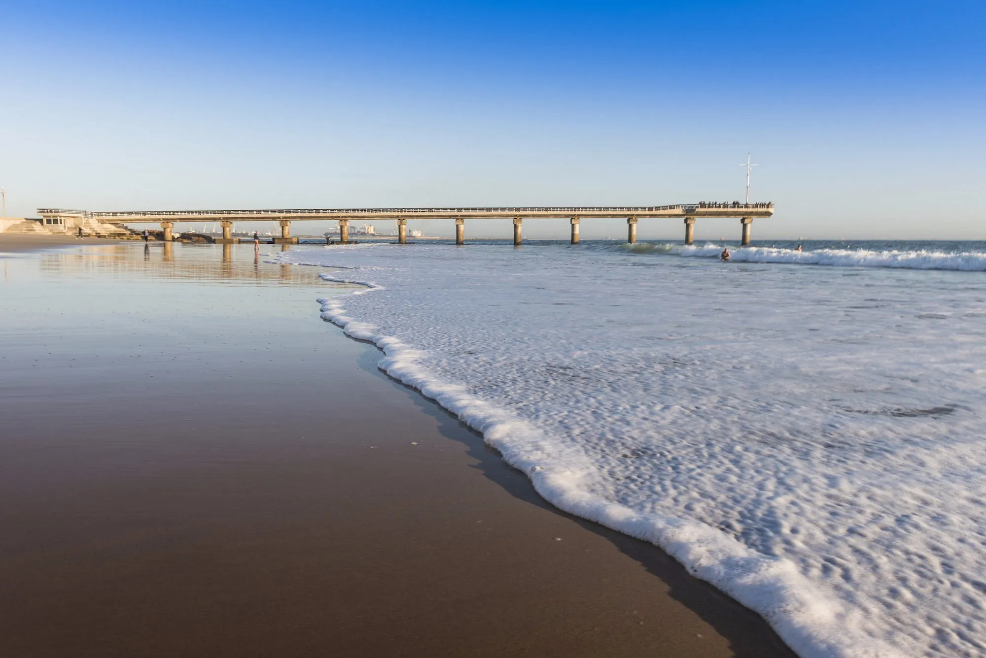 Blick auf einen Strandabschnitt mir einer Brücke, die ins Meer ragt