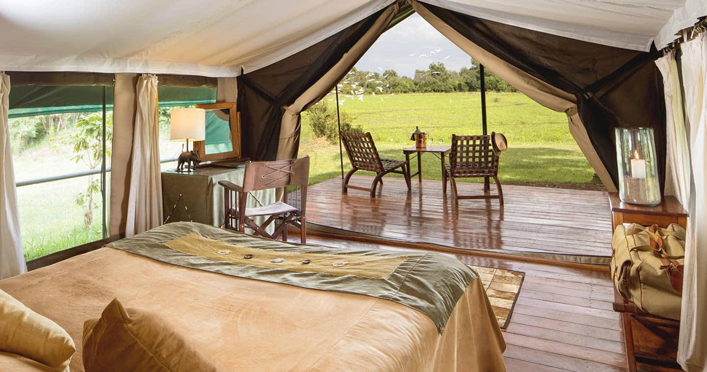 Blick aus einem Zelt mit Bett und sonstiger Einrichtung des Little Governors Camp, Kenia