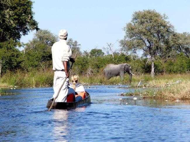 Personen im Mokoro Boot treiben über das Wasser