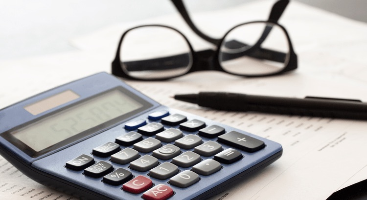 Calculator pen and glasses on paperwork that represent rental versus selling costs in Tampa Bay