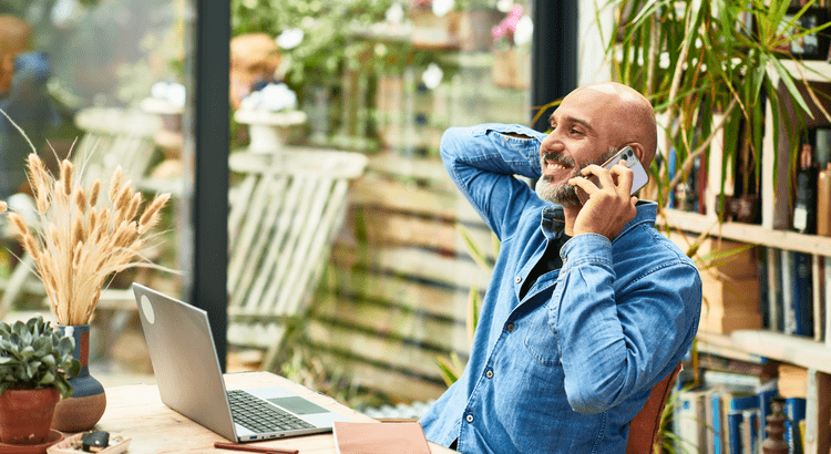 Man using a laptop and phone while working from a covered outdoor patio
