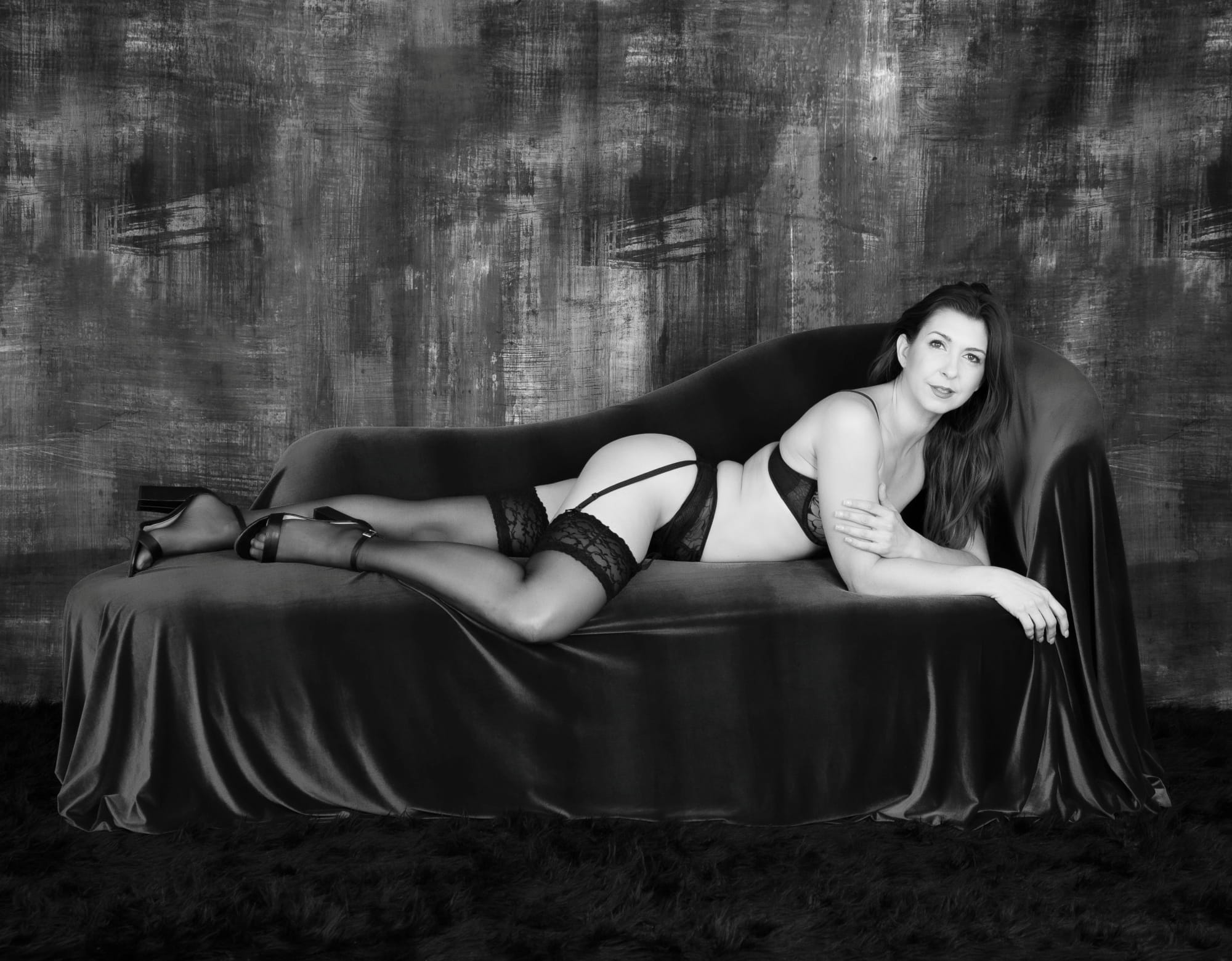 Confident woman in lingerie exudes sensuality and self love in intimate boudoir setting.