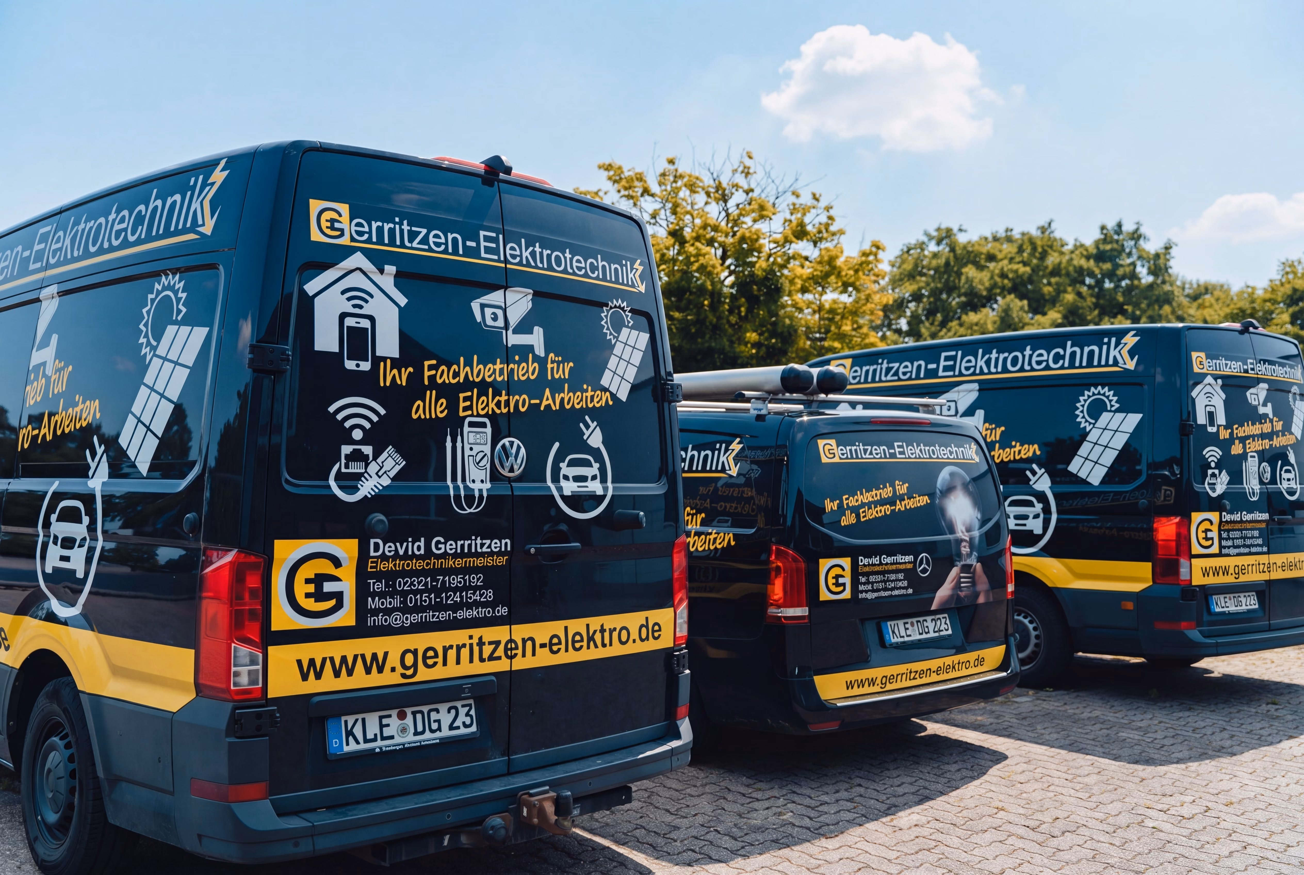 Drei beschriftete Firmenfahrzeuge von Gerritzen Elektrotechnik mit Logo und Leistungsübersicht stehen nebeneinander auf einem Parkplatz
