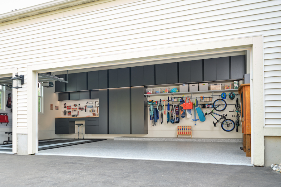 Modern garage with sleek black cabinets, workbench, and wall-mounted storage for tools, toys, and sports equipment.