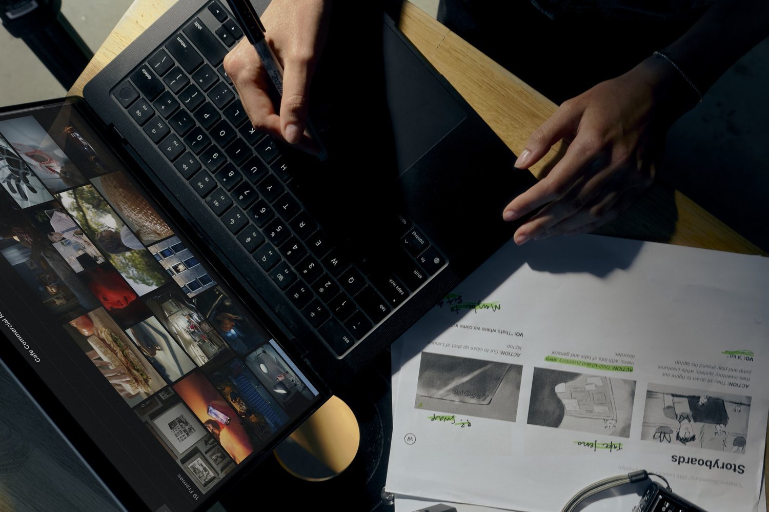 Overhead view of hands on a laptop and printed storyboards, with Frame Set open on a tablet