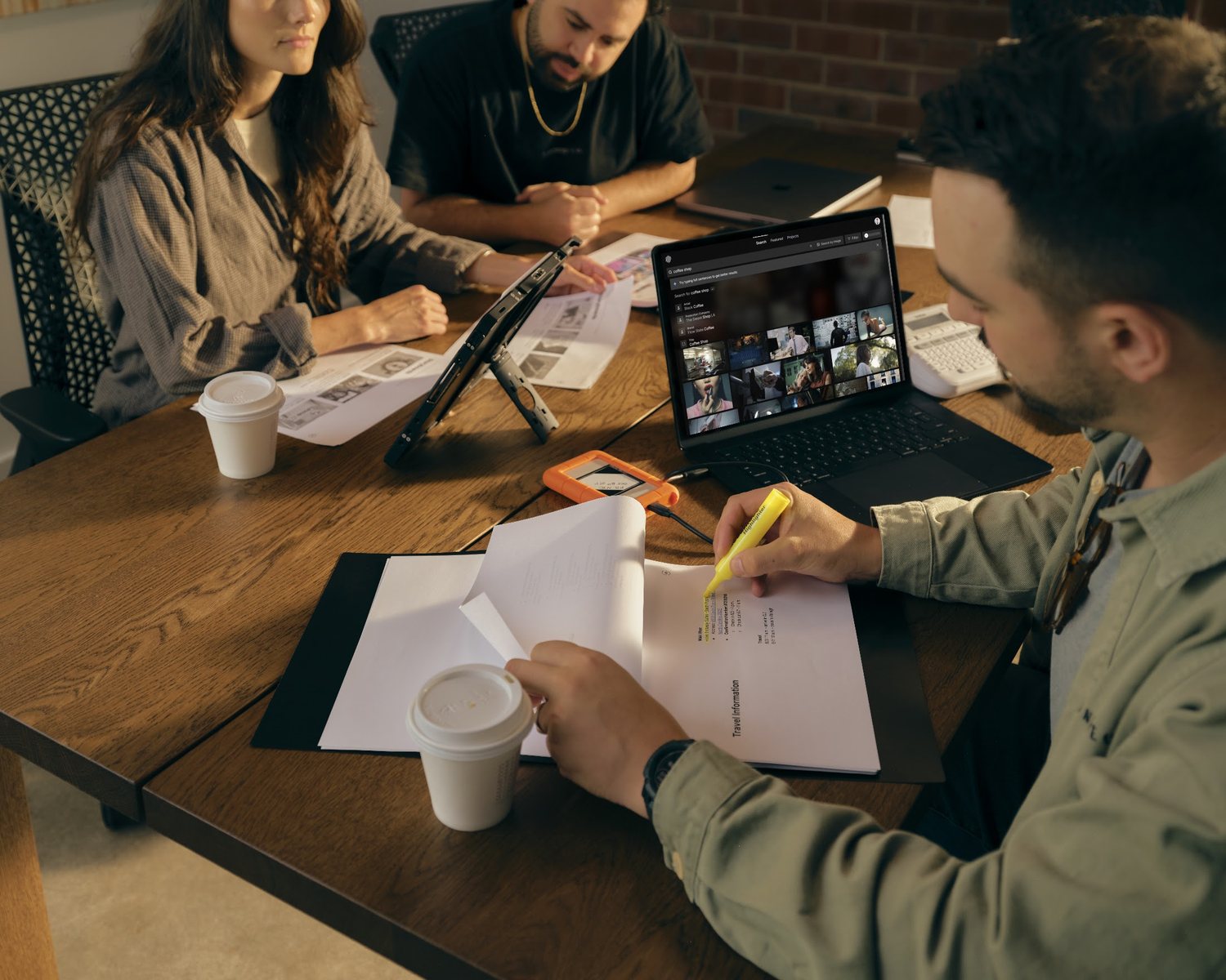 Three filmmakers working at a table with notes, coffee, and Frame Set open on a laptop and a tablet