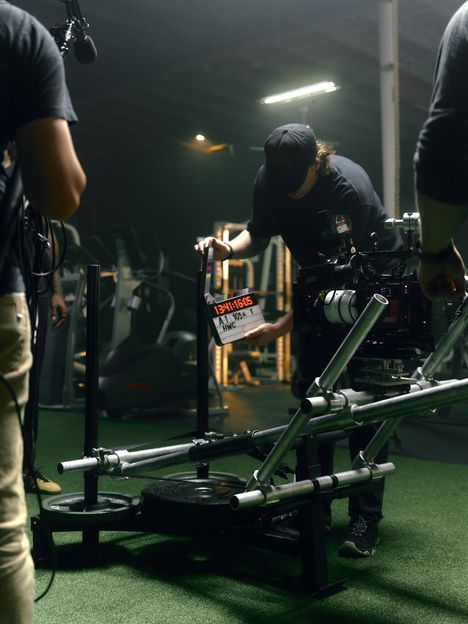 A cinema camera rides a slider inside a gym location