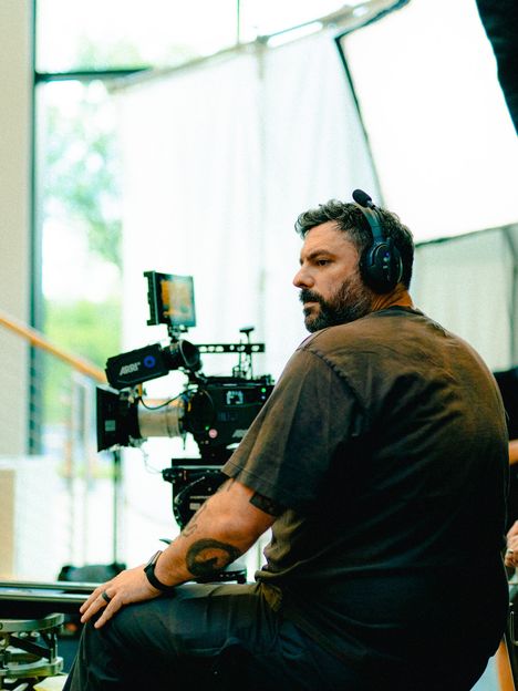 A director in headphones watches a monitor beside the camera