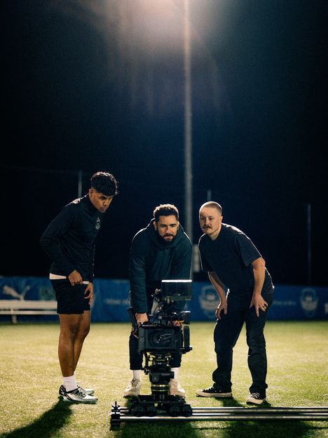 Three crew members huddle around a monitor on a night shoot