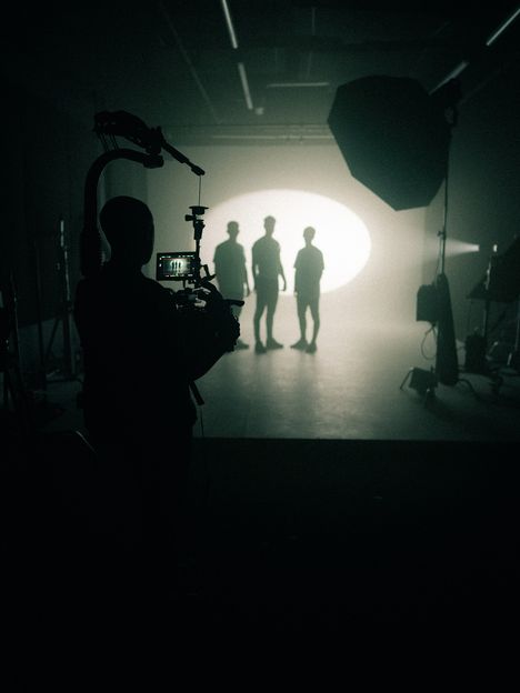 Crew silhouettes stand in front of a large backlight on a dark stage