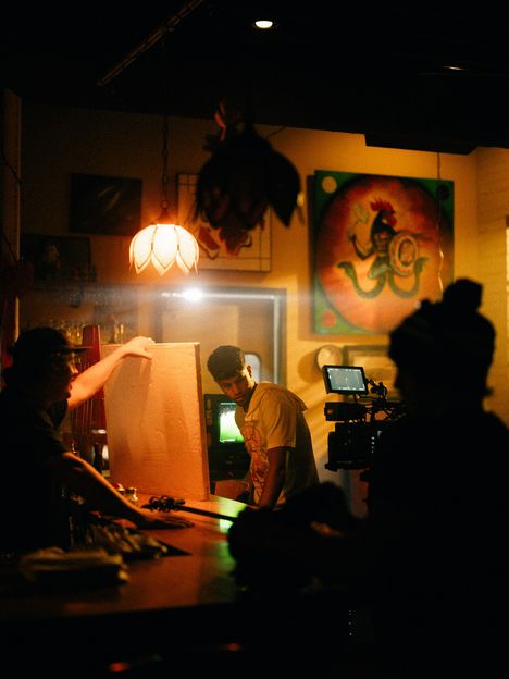 A crew lights a small warm interior set around a bounce card