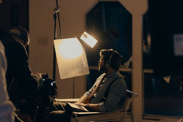 A performer sits under a soft light on a quiet interior set