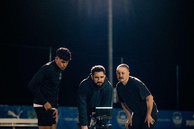 Three crew members huddle around a monitor on a night shoot
