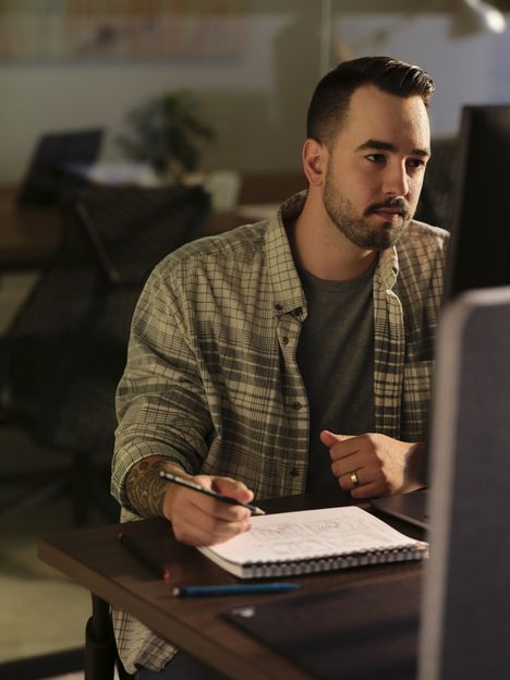 A filmmaker sketching storyboard panels at a desk beside a monitor