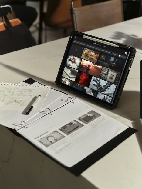 A tablet running Frame Set on a table beside printed storyboard pages
