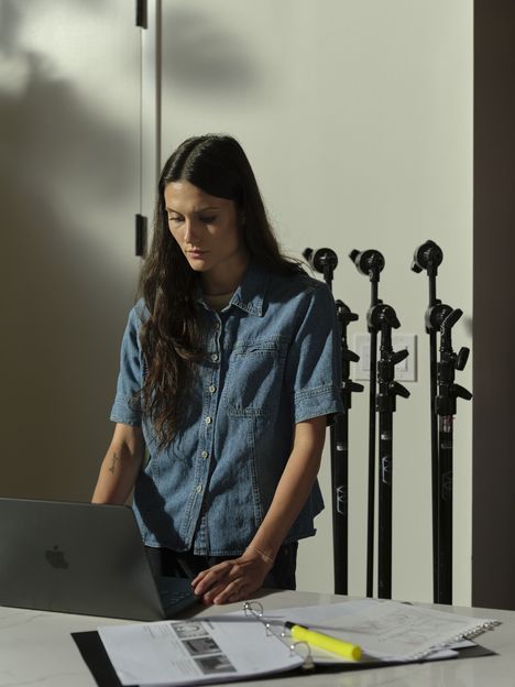 A filmmaker at a standing desk among light stands in a studio