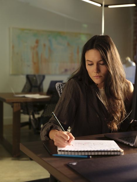 A filmmaker writing notes in a sketchbook at a long studio table
