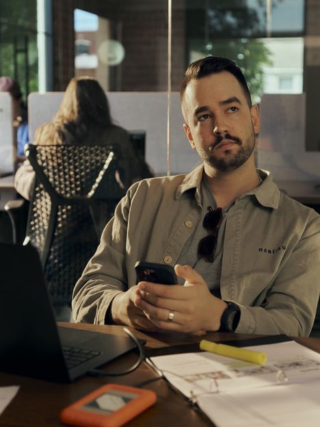 A filmmaker checking a phone at a prep table with a tablet running Frame Set