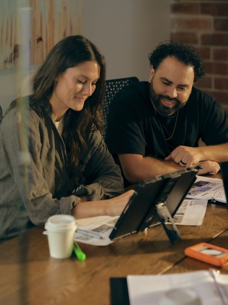 Two collaborators laughing over a tablet during a prep session