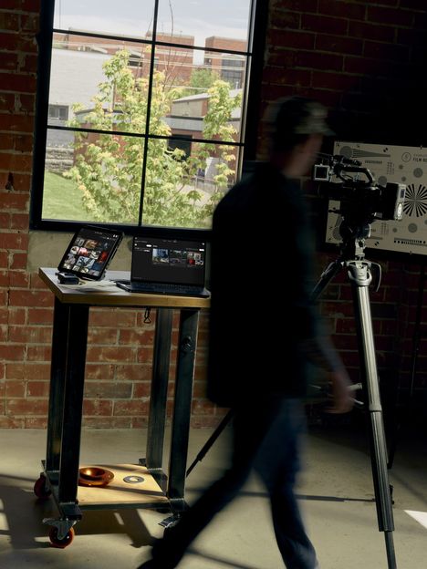 A figure walking past monitors and a camera in a brick studio