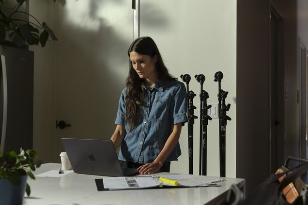 A filmmaker working at a standing desk among light stands
