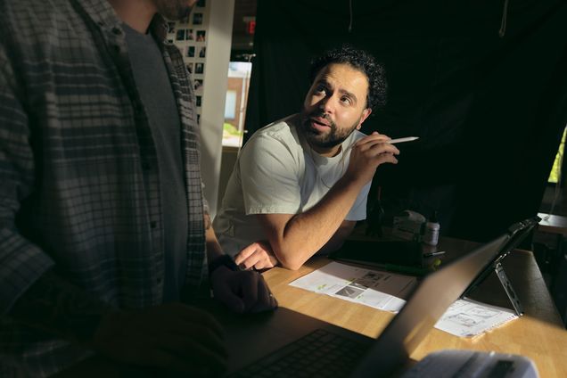 Two filmmakers talking across a table during prep