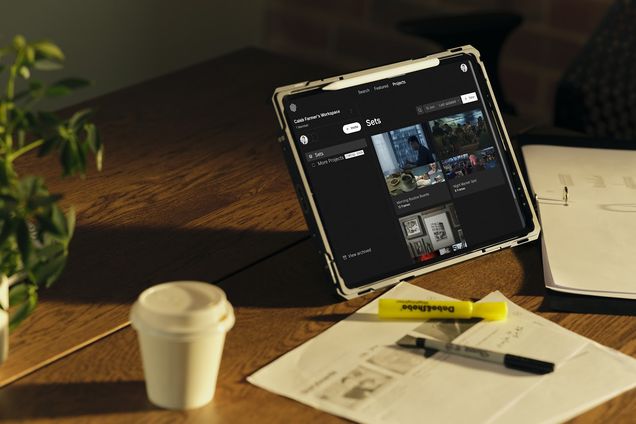 A tablet running Frame Set beside a coffee cup and printed storyboards
