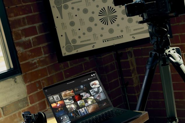 A laptop running Frame Set beside a camera on a tripod in a brick studio