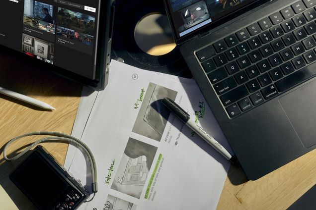 A laptop running Frame Set under a desk lamp beside headphones