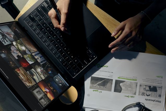 Hands on a laptop running Frame Set over printed storyboard pages