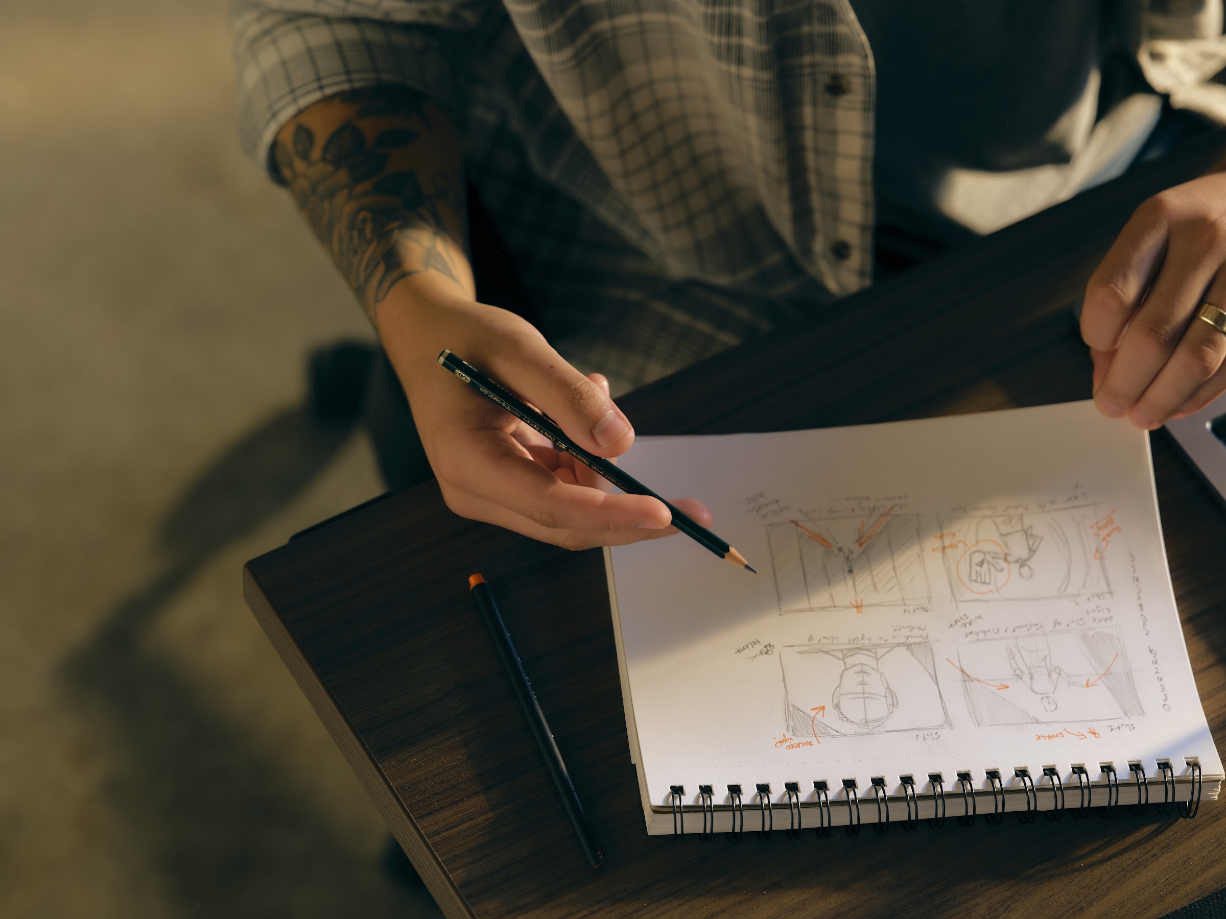 Overhead view of hands sketching a storyboard in a notebook during pre-production.