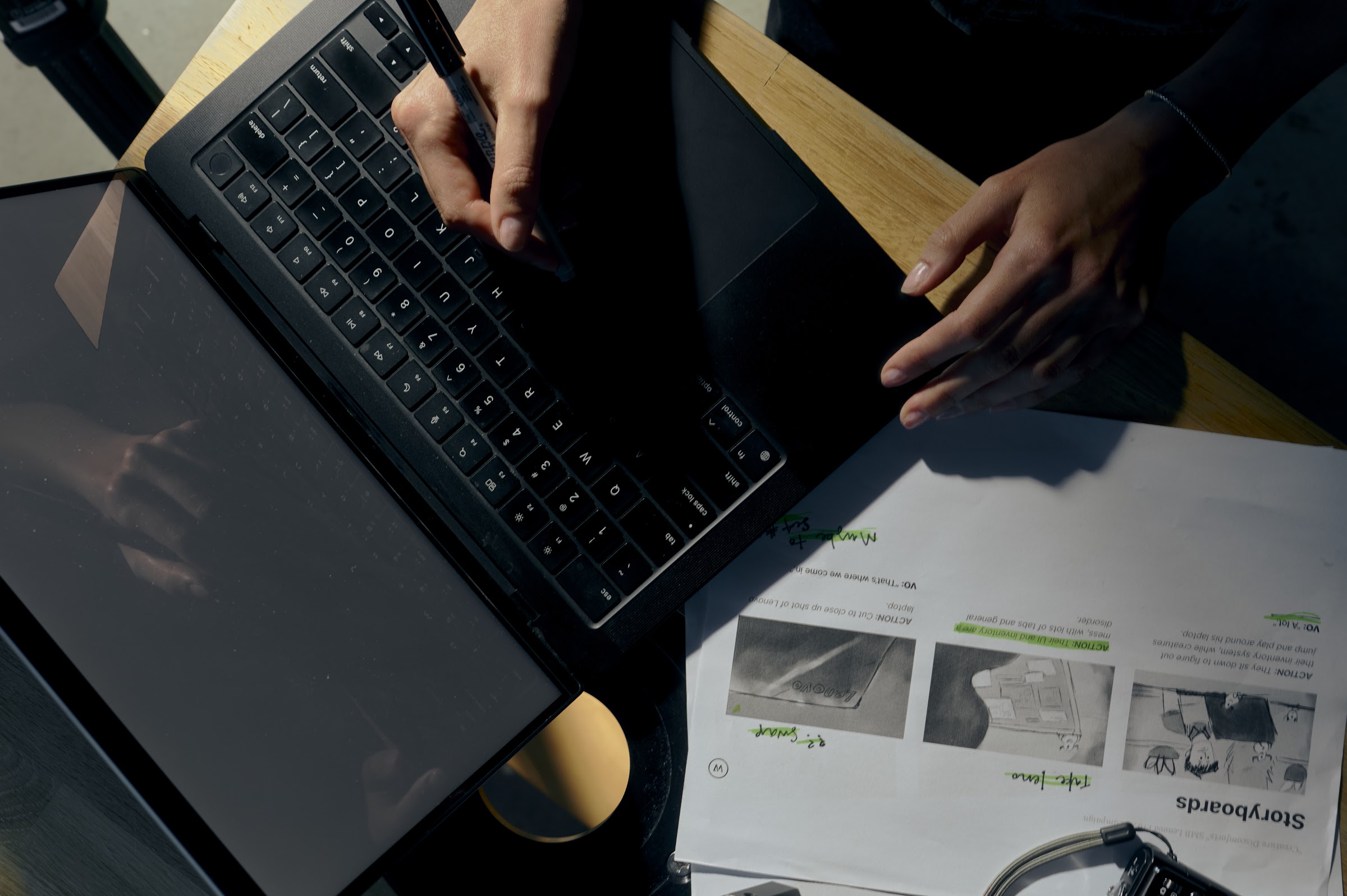 Overhead view of a filmmaker typing on a laptop beside script pages during pre-production.