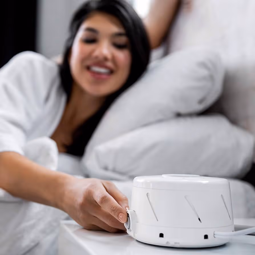 Woman tuning in white noise fan from bed. 