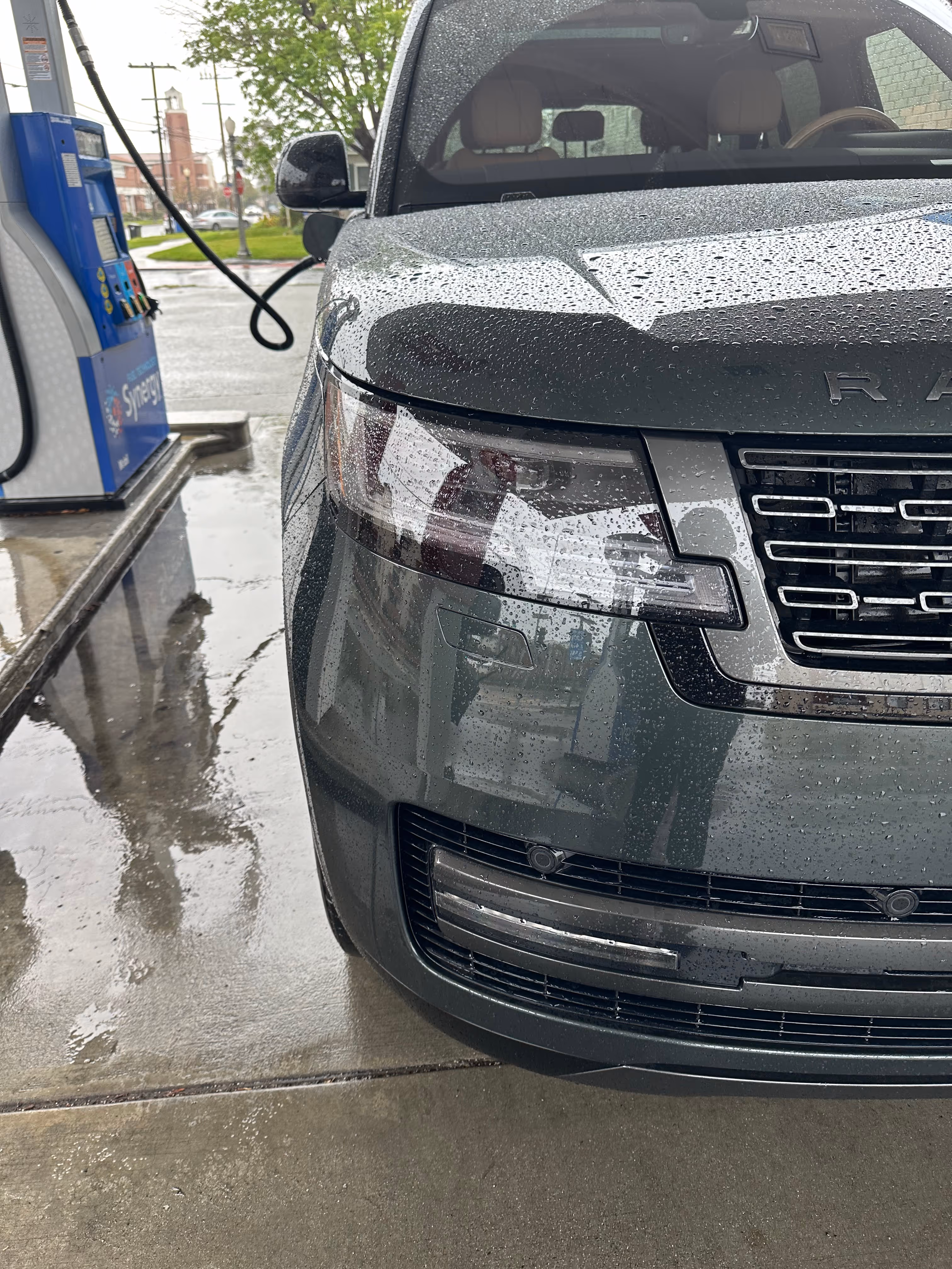 Car refueling at a gas station with fuel pump nozzle inserted